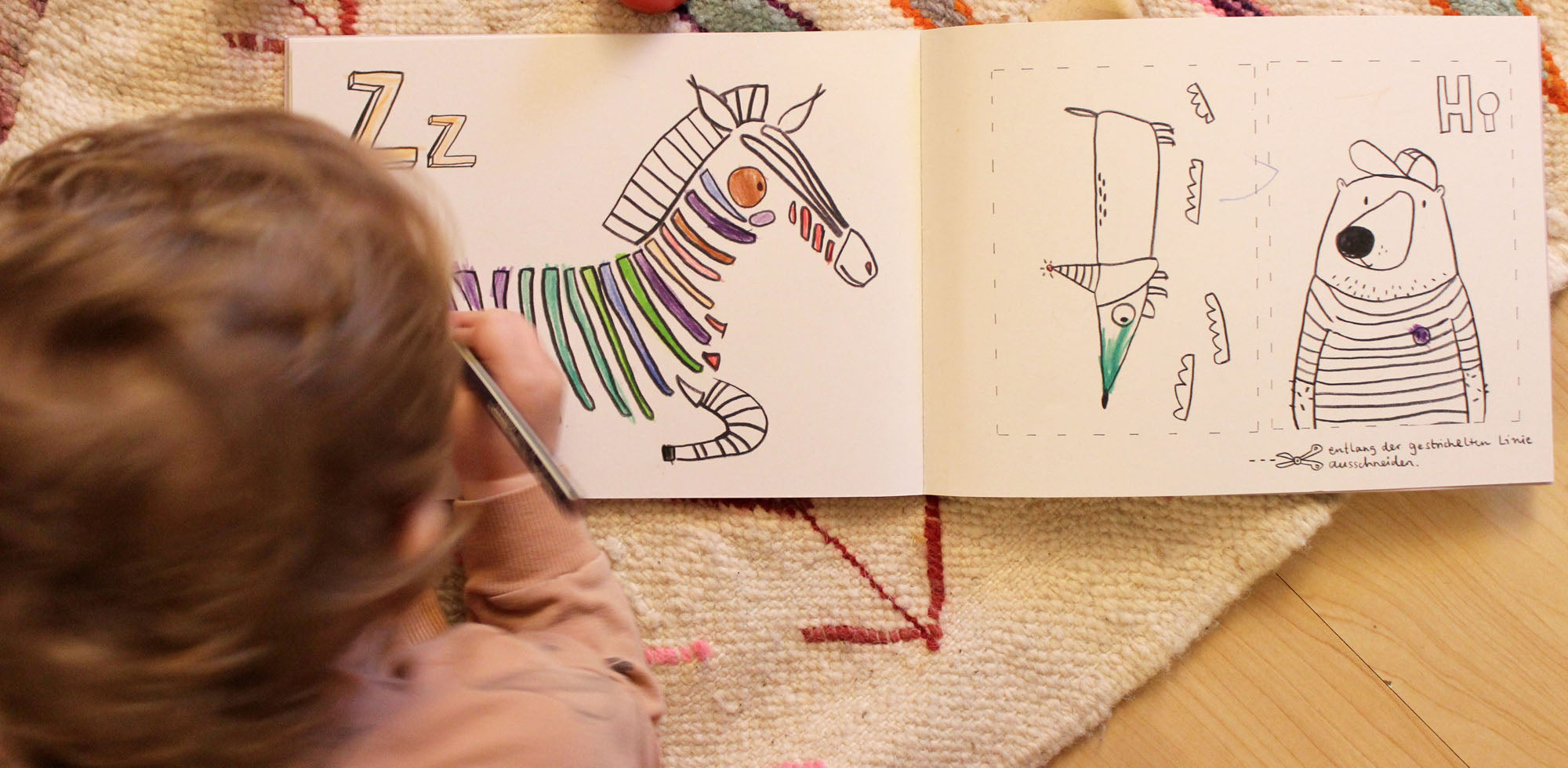 Kind malt in einem ABC Ausmalbuch von halfbird ein zebra aus