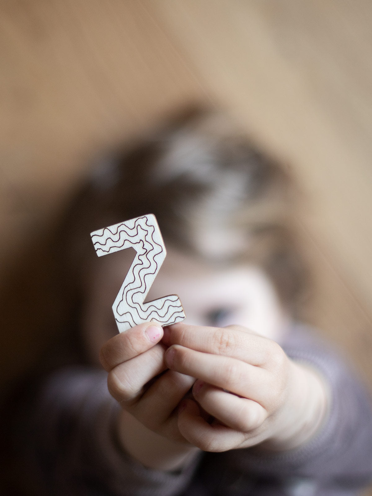 Kind hält einen Holzbuchstaben Z hoch