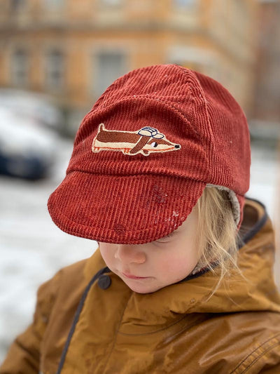 Kind trägt eine rote cord mütze mit Dackel Aufnäher vorne drauf