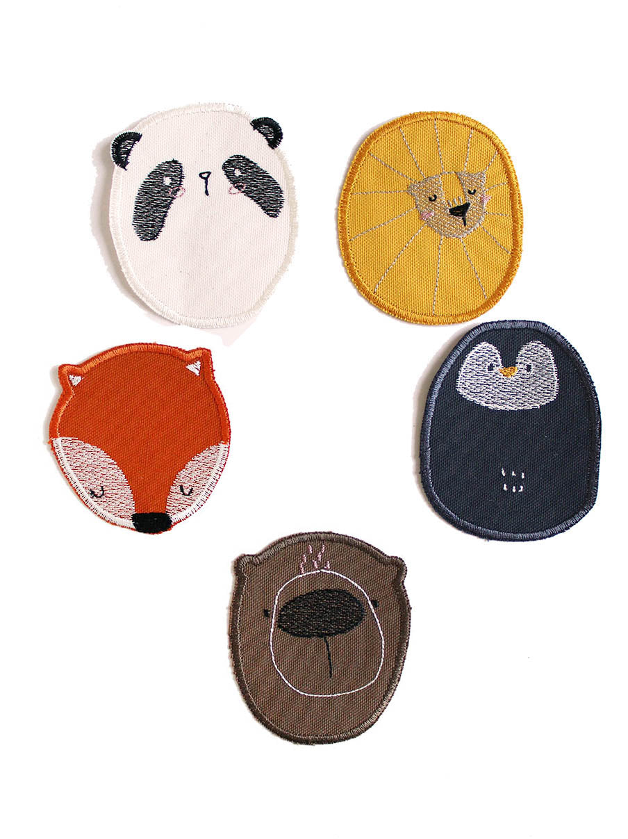 fünf verschiedene Knieflicken in Tierform. Darunter Löwe in gelb, Panda in weis schwarz, Pinguin in schwarz, Bär in Braun und fuchs in rot