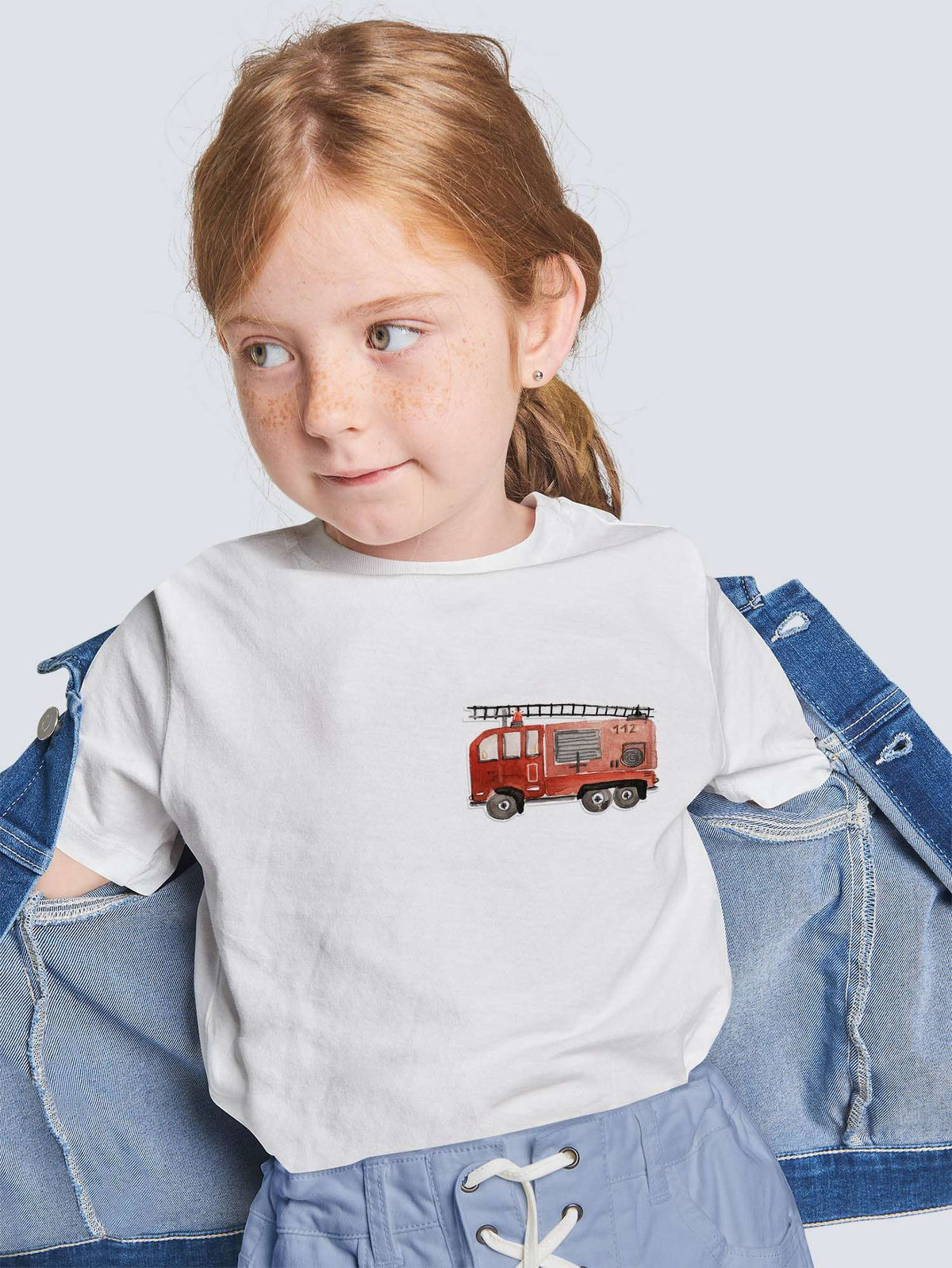 Kind trägt ein shirt mit einem feuerwehr bügelbild in rot und eine jeansjacke