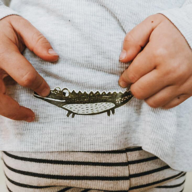 Bügelbild Krokodil auf einem rippshirt und das kind hält seine hände dort hin