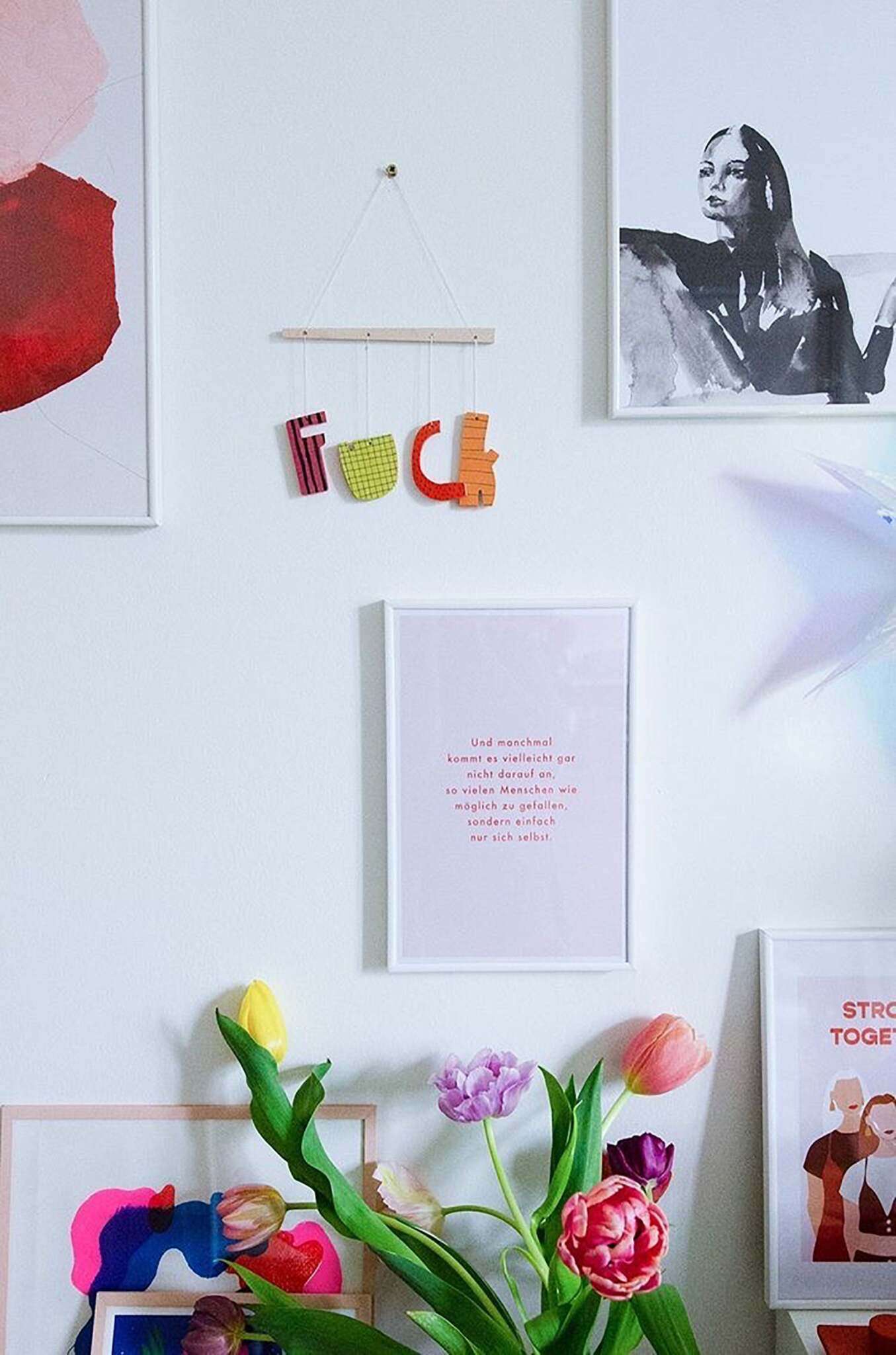 Fuck Mobile aus Holz in bunt an einer Wand mit Postern, Sprüchen und Tulpen