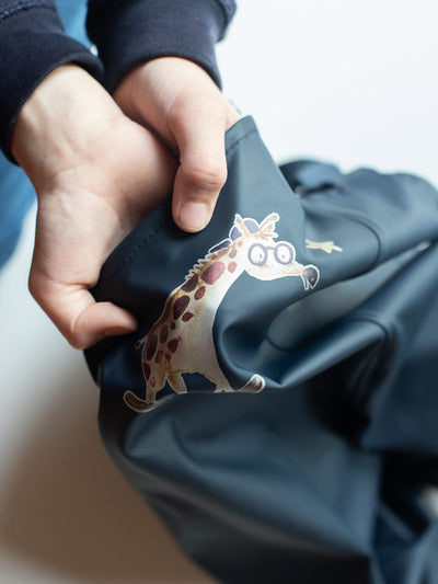 Ein reflektierendes Bügelbild von Halfbird (Motiv: Giraffe) auf einer blauen Regenhose