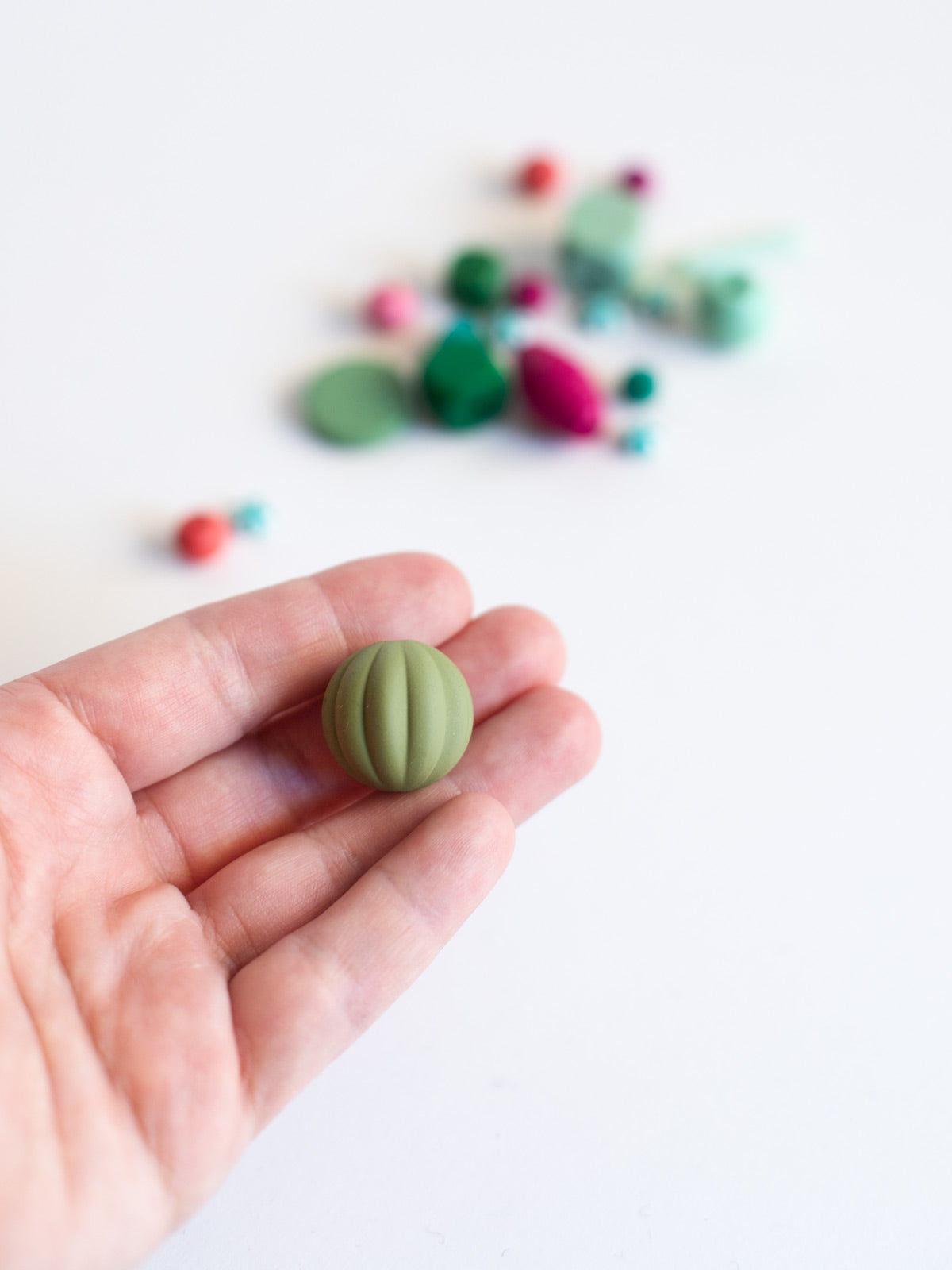 Hand mit grüner melonenförmigen Perle aus dem Perlenset "Watermelon" von Halfbird