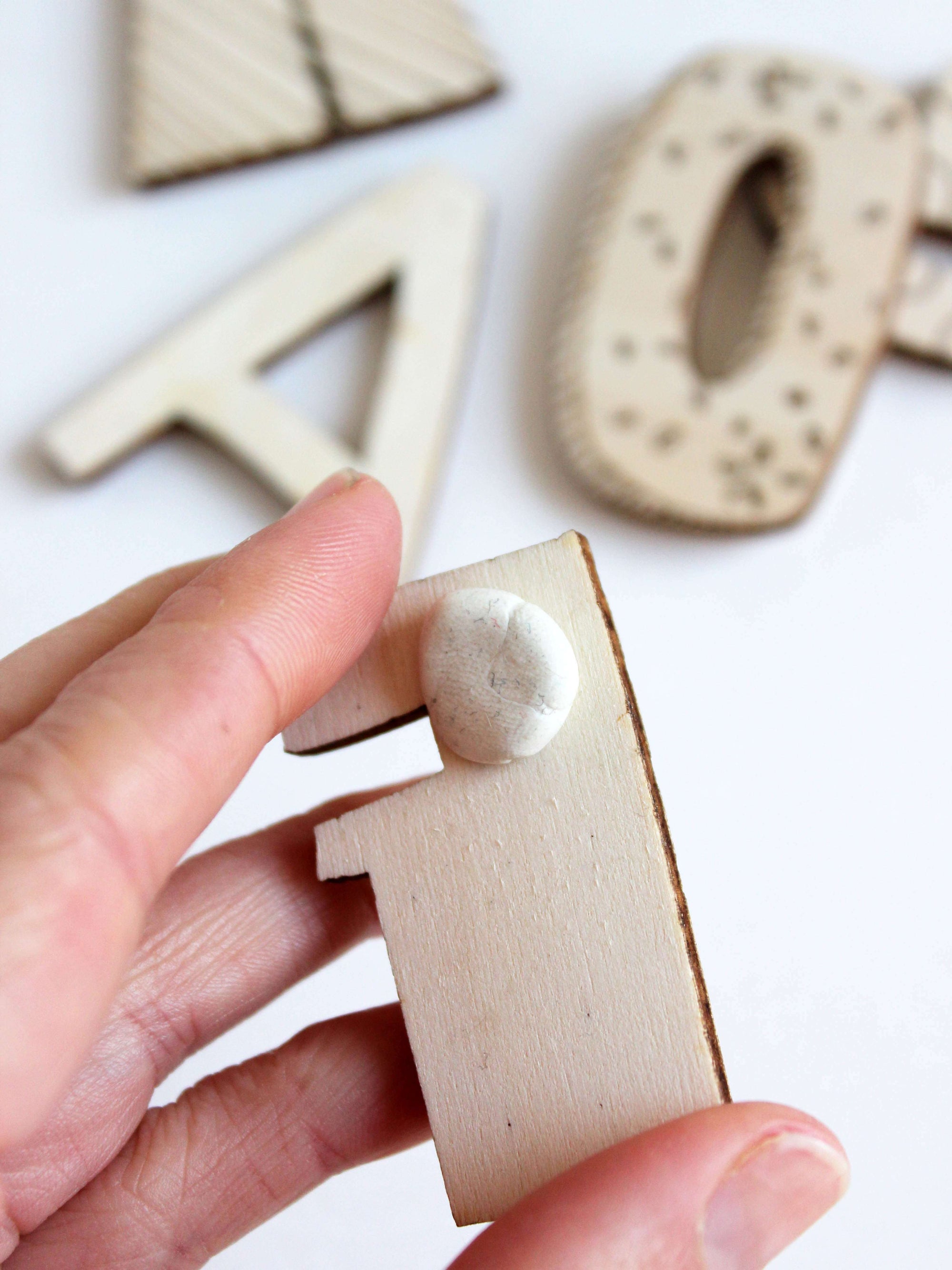 auf einem Holzbuchstaben F klebt Uhu klebeknete