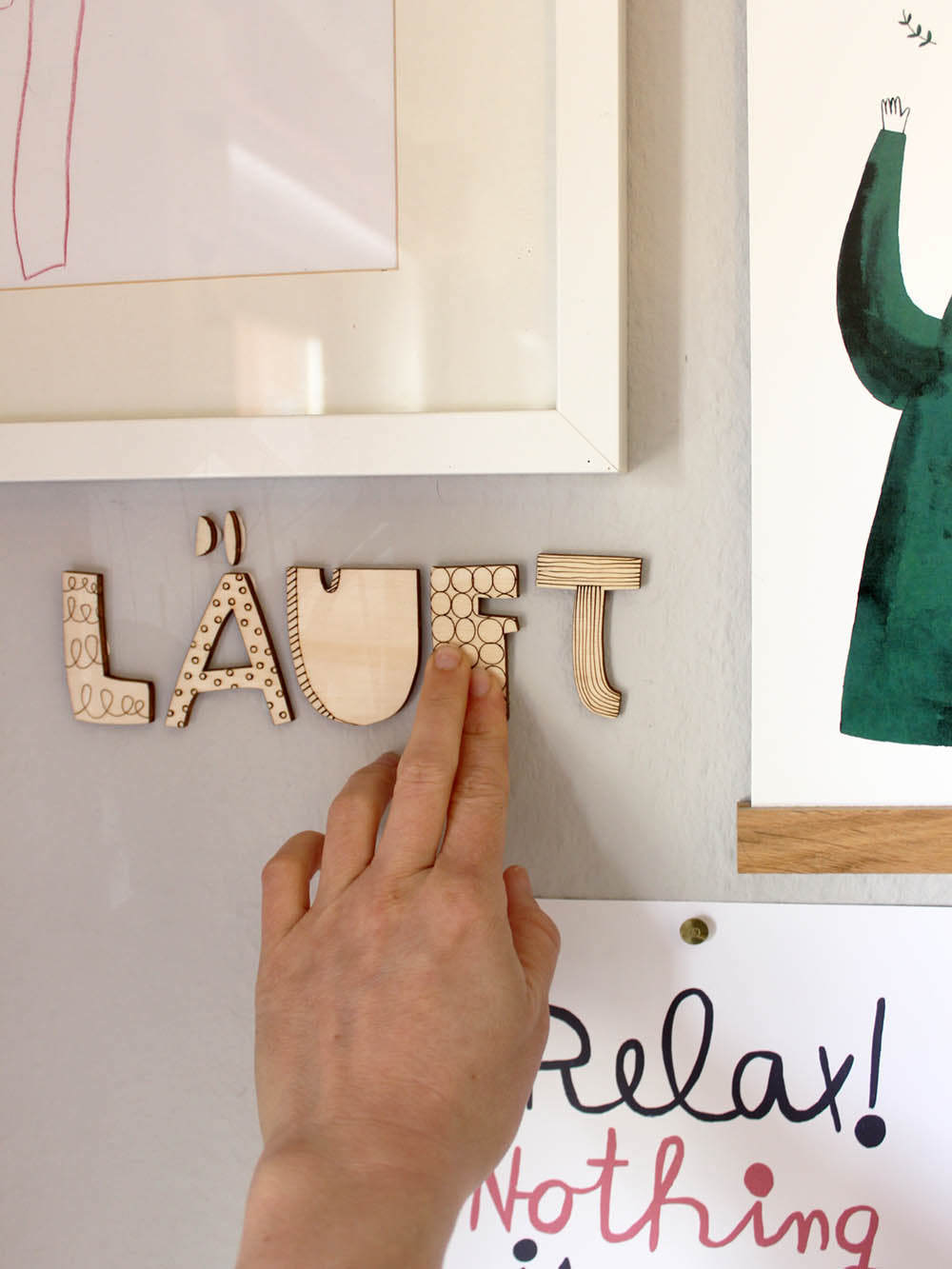 Das Wort Läuft an der Wand neben anderen Postern im Arbeitszimmer. Eine Hand klebt den Buchstaben F an