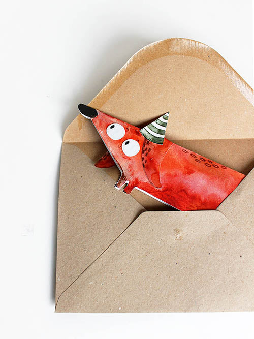 Geburtstagseinladung Dackel mit Partyhut in rot in einem braunen Umschlag