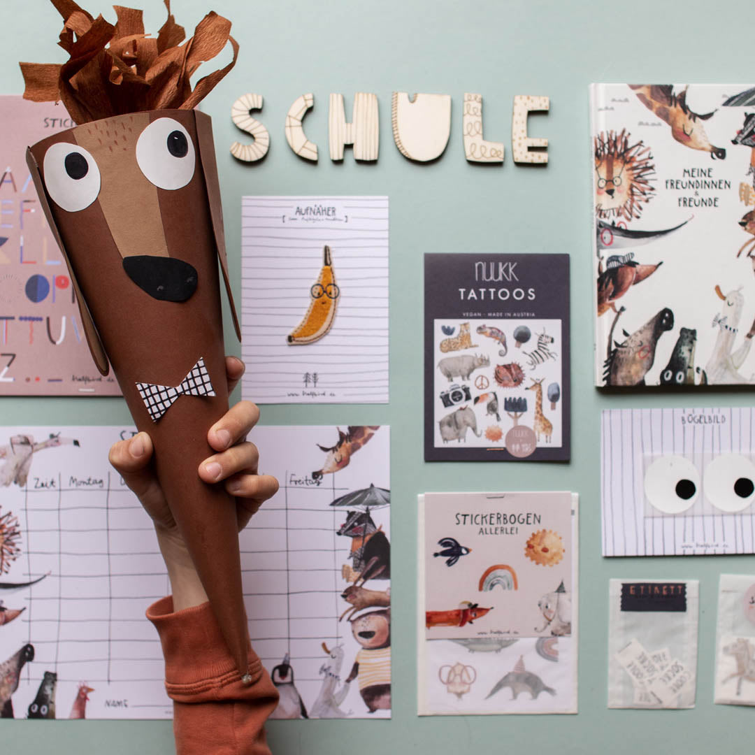 Kind hält eine Dackel schultüte hoch dahinter liegen geschenke zur Einschulung