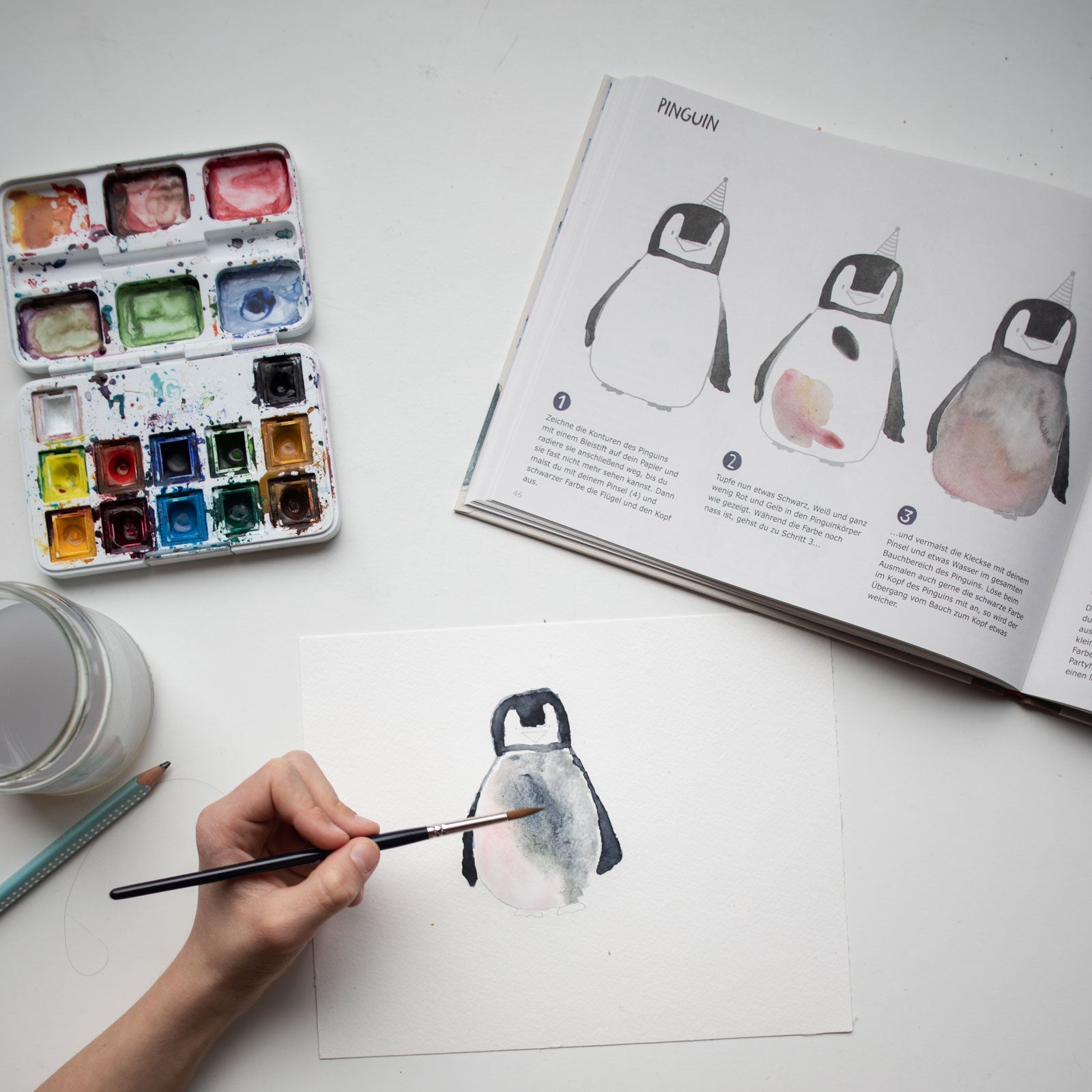 Kind malt einen Pinguin aus dem Schritt für Schritt Krummtier-Aquarellbuch