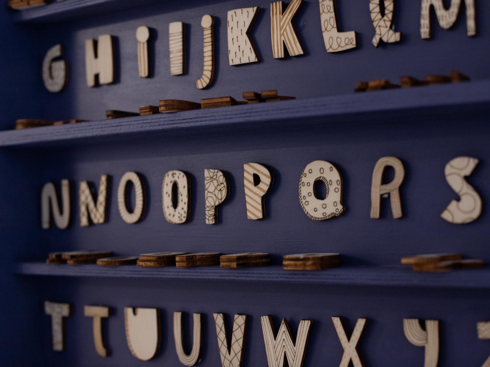 Buchstaben aus Holz gelasert in einem Setzkasten in dunkel blau