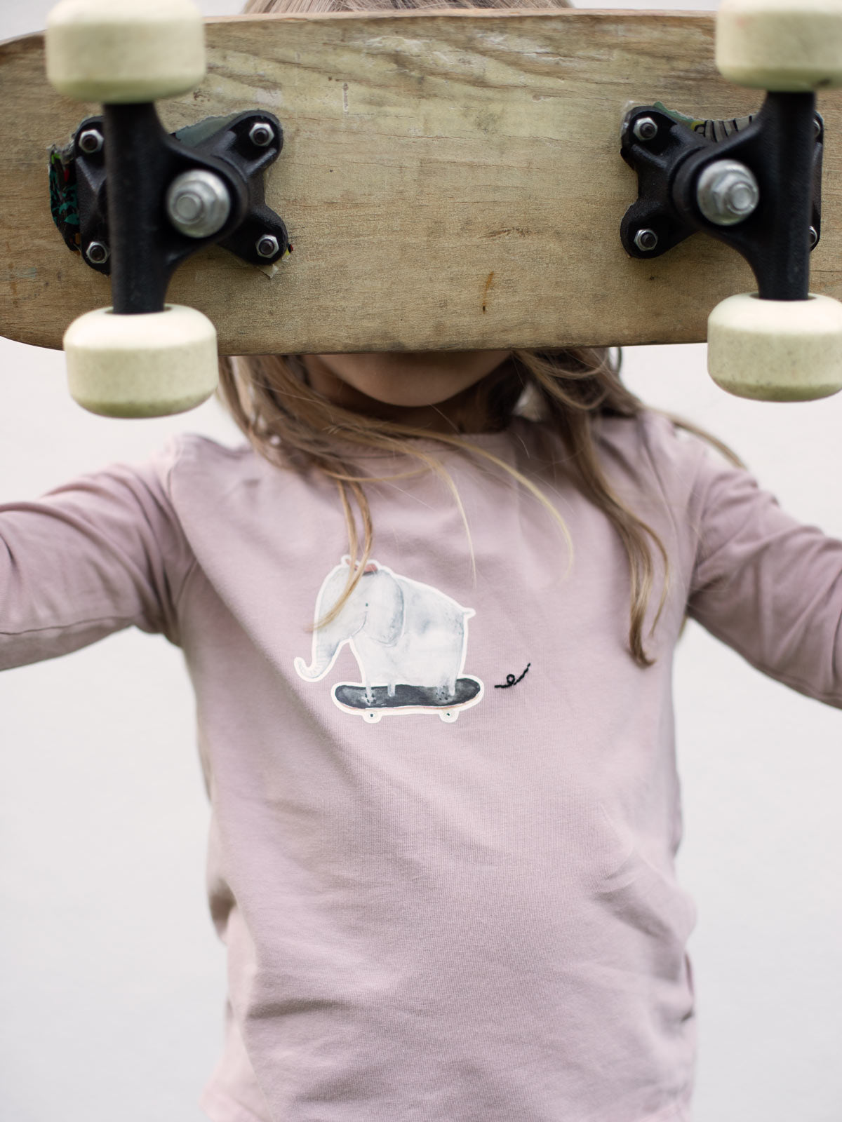 Kind mit Skateboard und rosafarbenem Shirt mit dem Bügelbild "Elefant mit Skateboard" von Halfbird