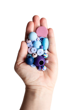 Hand mit Perlenset Kristallblau von Halfbird mit fliederfarbenem Bäckergarn