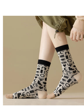 Trageansicht von der Seite von Socke mit Formen und Muster in schwarz und weiß mit beigem Zwickel und weißer Ferse