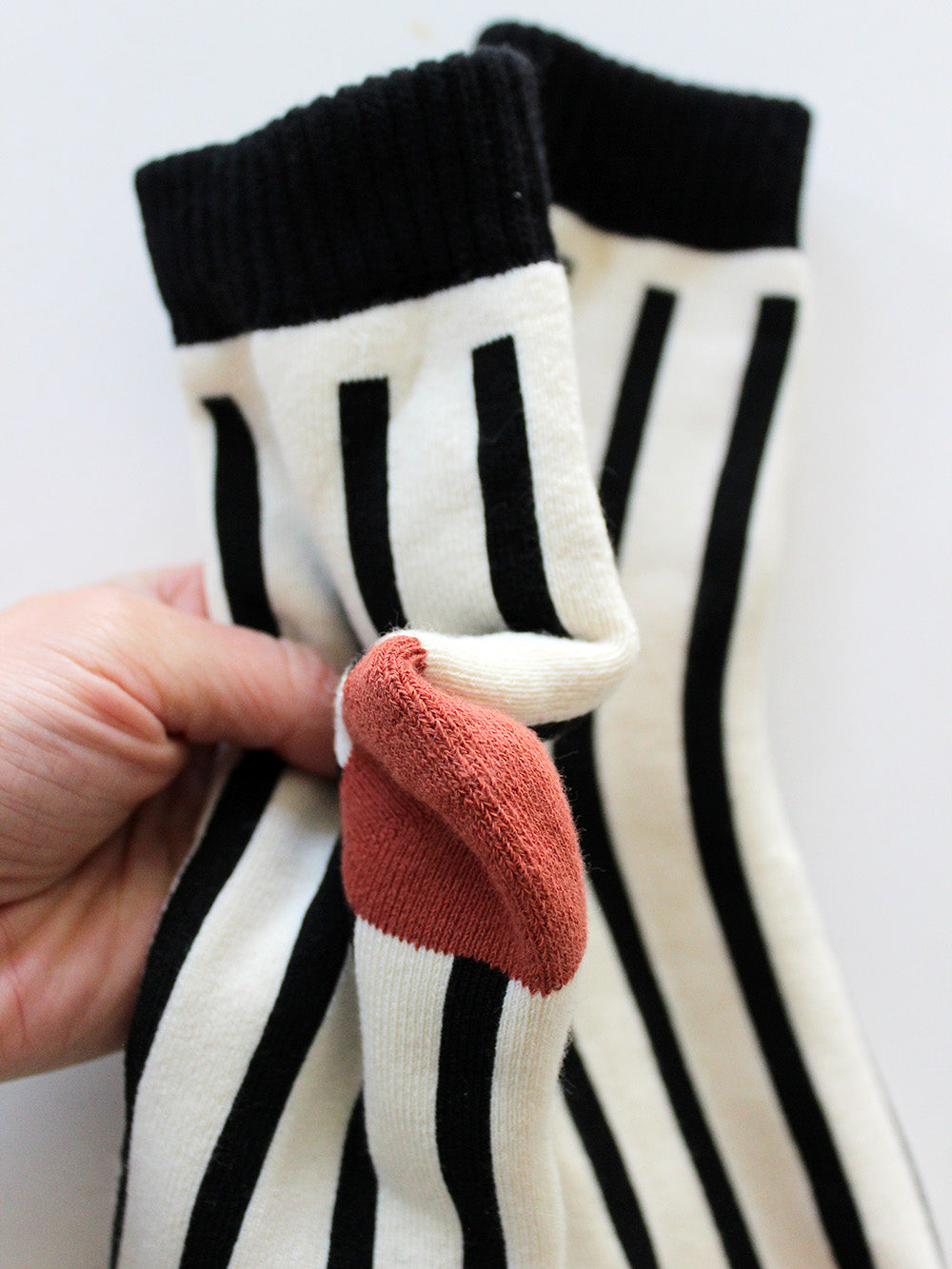 Nahansicht Socken in weiß mit schwarzen Streifen und Bündchen mit orangenem Zwickel und Ferse