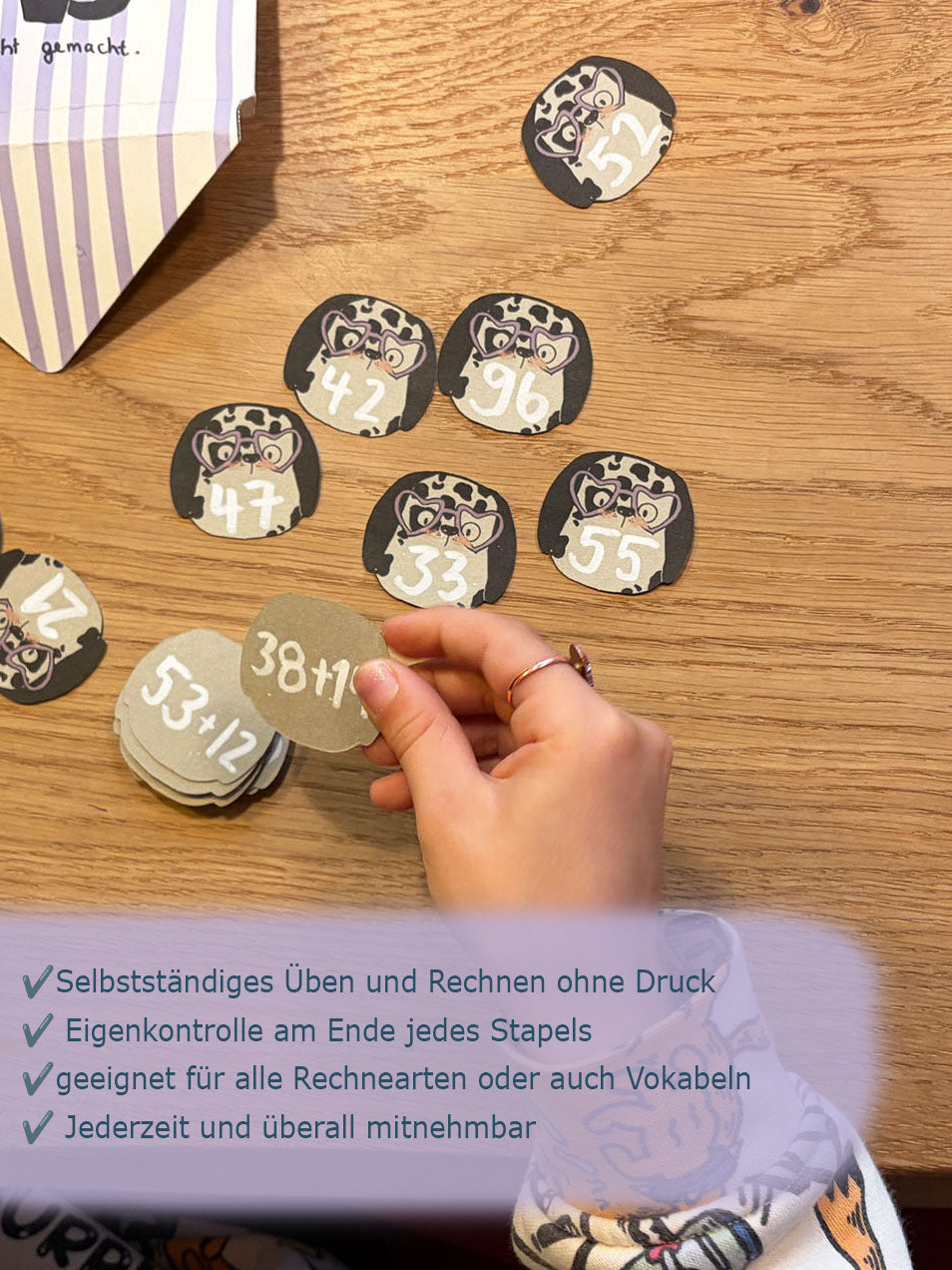 Kind spielt am Tisch mit den Stapelkarten von Halfbird im Dalmatiner-Design mit Rechenaufgaben drauf geschrieben