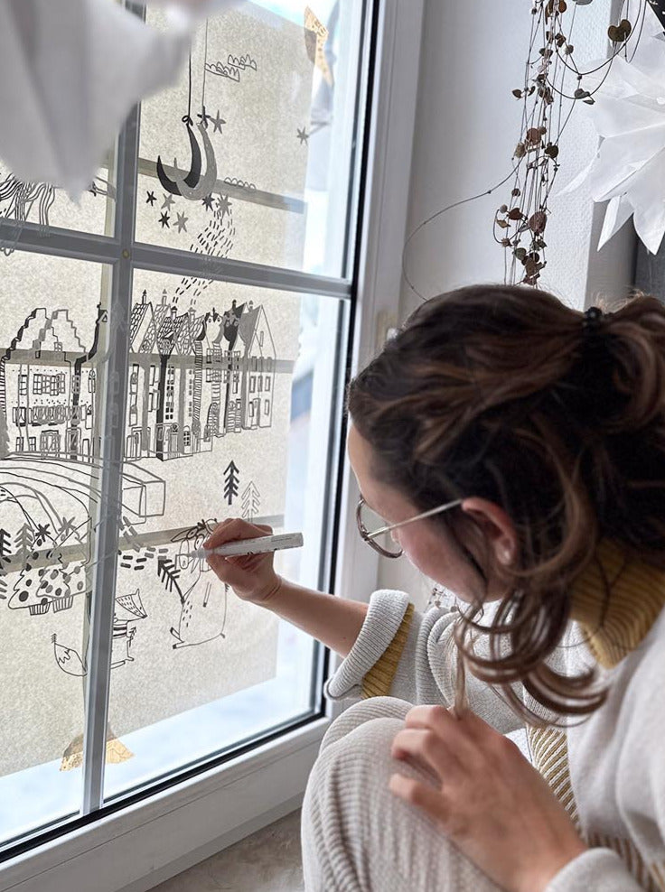 Frau malt ein Fenster mit weißem kreidestift an