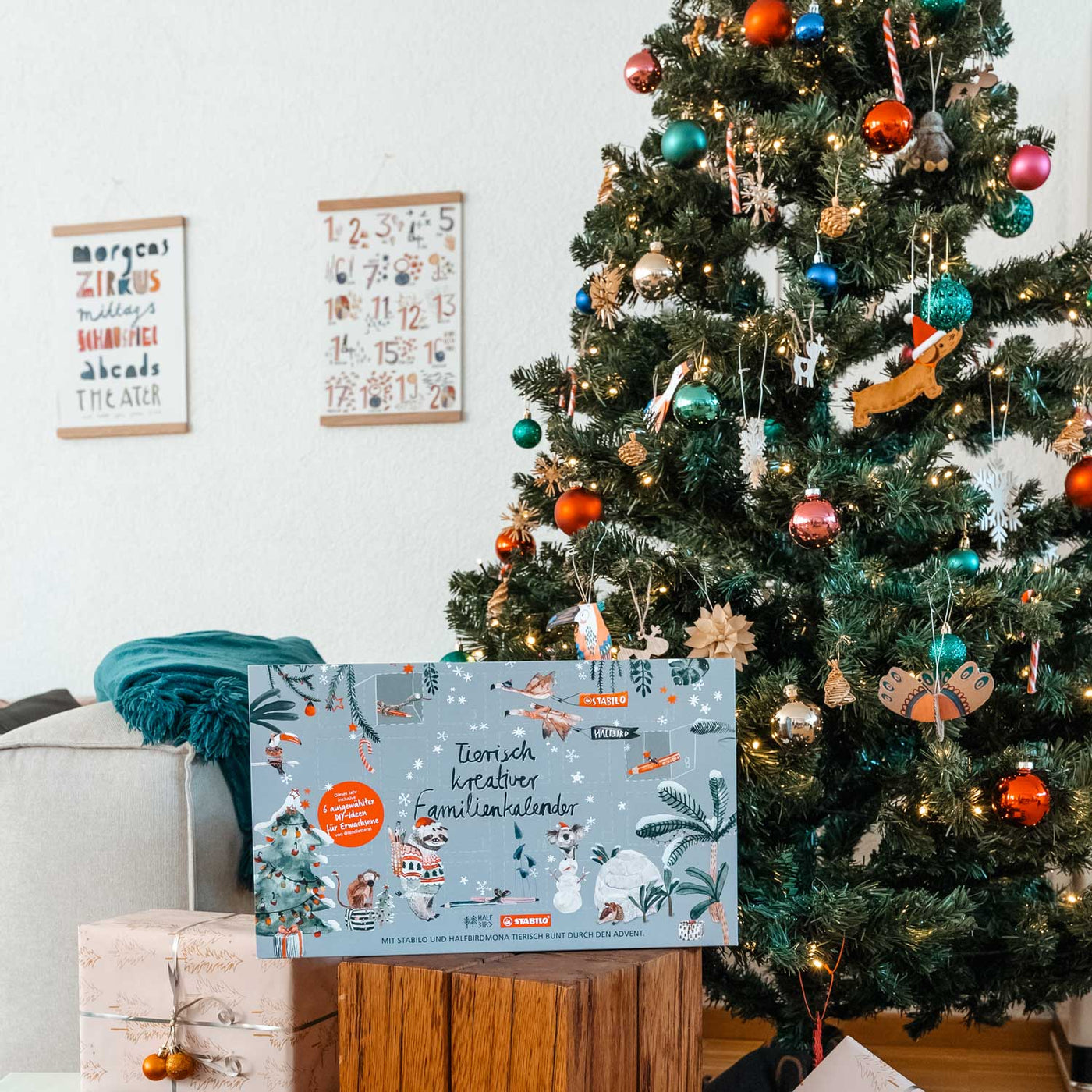 Adventskalender von Halfbird und Stabilo vor einem geschmückten Weihnachtsbaum
