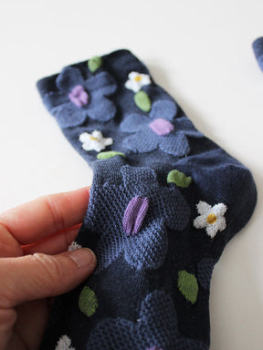 Detailansicht von dunkelblauen Socken mit erhabener Struktur mit großen taubenblauen und weißen Blumen