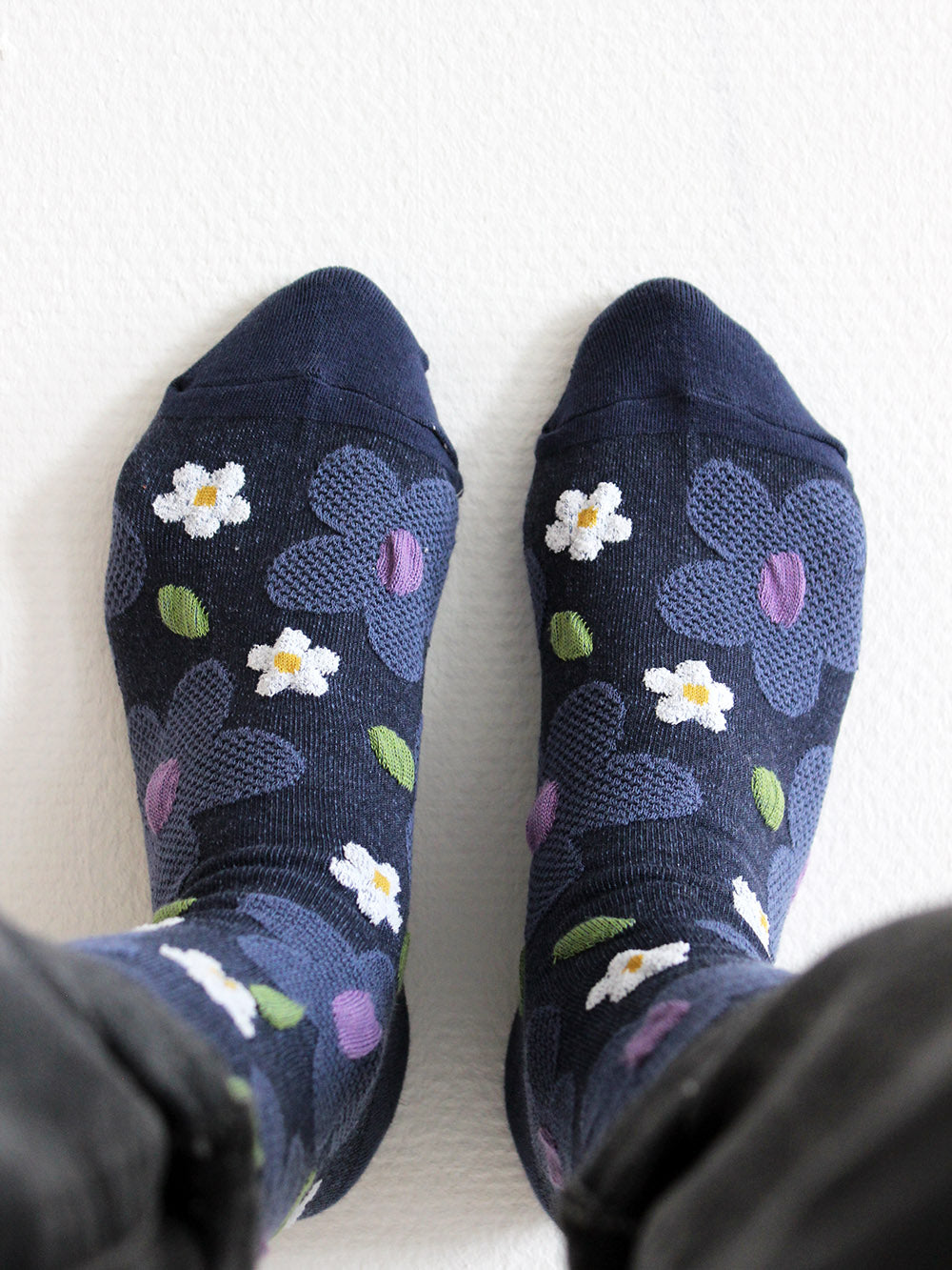 Tragebild von dunkelblauen Socken mit erhabener Struktur mit großen taubenblauen und weißen Blumen