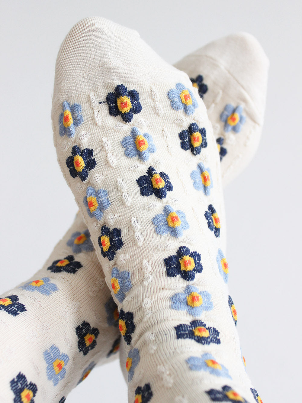 Tragebild von Cremefarbenen Socken mit Stickerei Anmutung und hellblauen und dunkelblauen Blumen mit gelb/roten Blütenstempeln