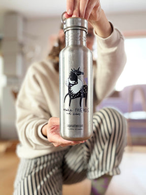 Mona hält Edelstahlflasche mit transparentem Vinylsticker Make Friends not Likes mit Pferd- und Schwanmotiv von Halfbird