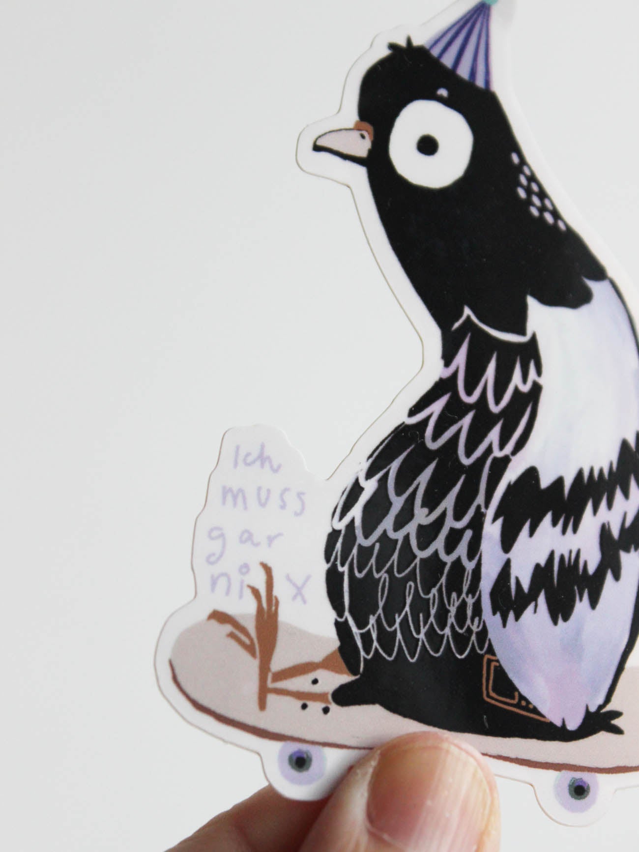 Hand mit glitzerndem Vinylsticker Taube auf Skateboard mit der Aufschrift Ich muss gar nix von Halfbird