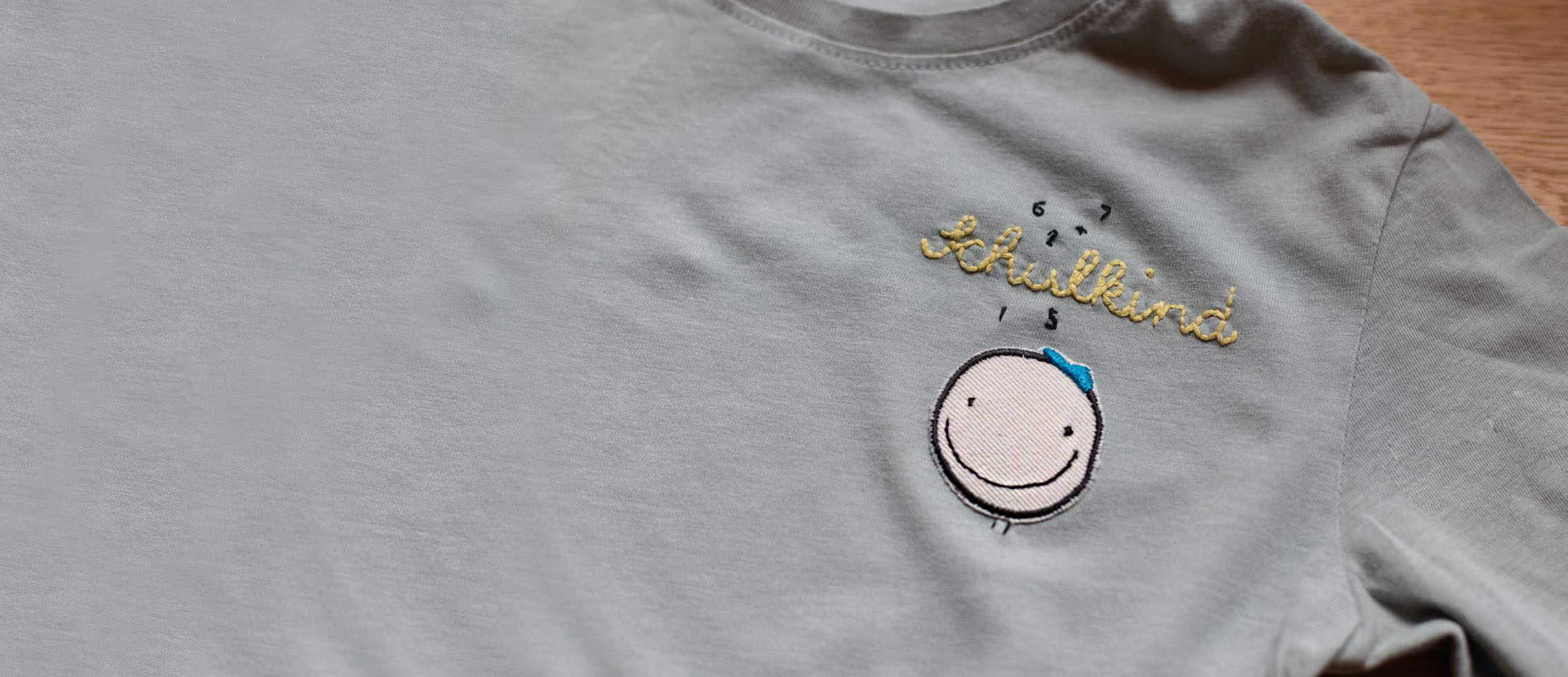 ein tshirt ist mit einem smiley aufnäher verziert, darüber wurde das wort schulkind gestickt und zahlen