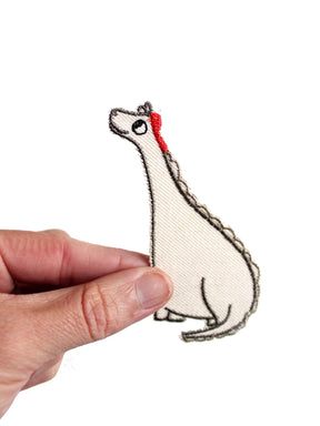 Aufnäher Dino mit roter Kappe aus Biobaumwolle in der Hand gehalten