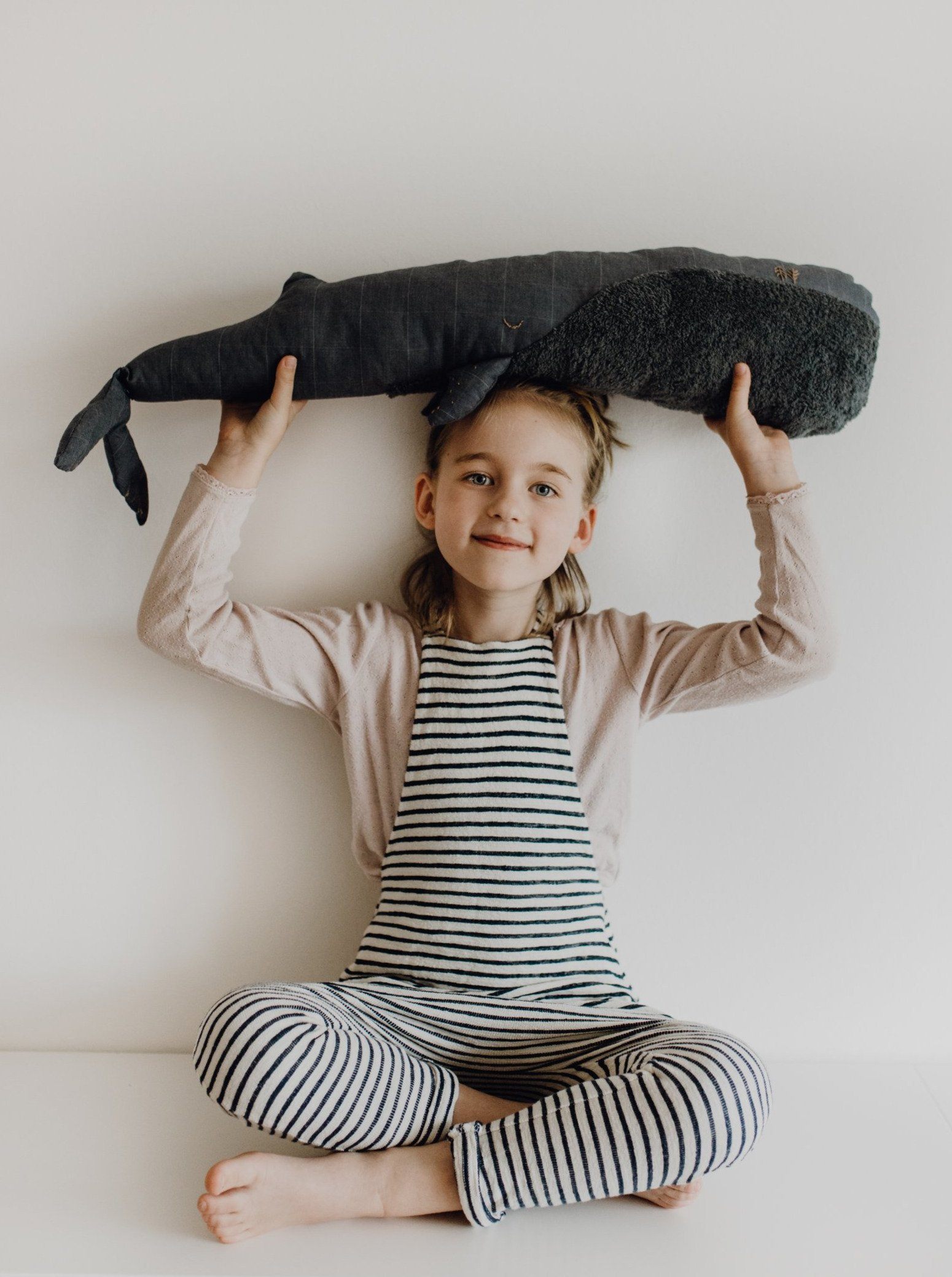 Kind hält Kuscheltier Wal auf dem Kopf