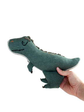 Hand hält eine T-rex Kuscheltier in grün nach oben