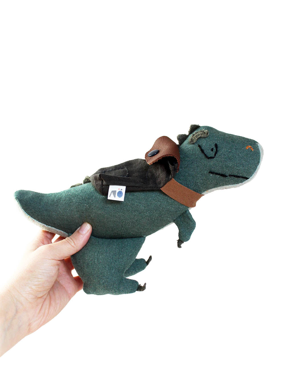 Hand hält einen genähten t-rex in grün mit einem Rucksack nach oben