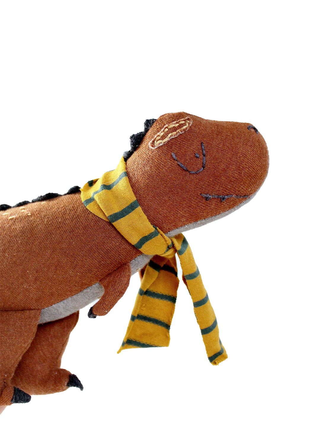 t-rex als Kuscheltier in rostrot mit einem gestreiften Schal in gelb grün
