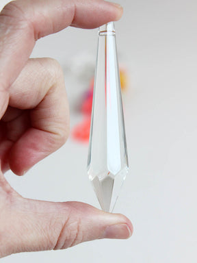 Regenbogenkristall in Zapfen form in der Hand haltend