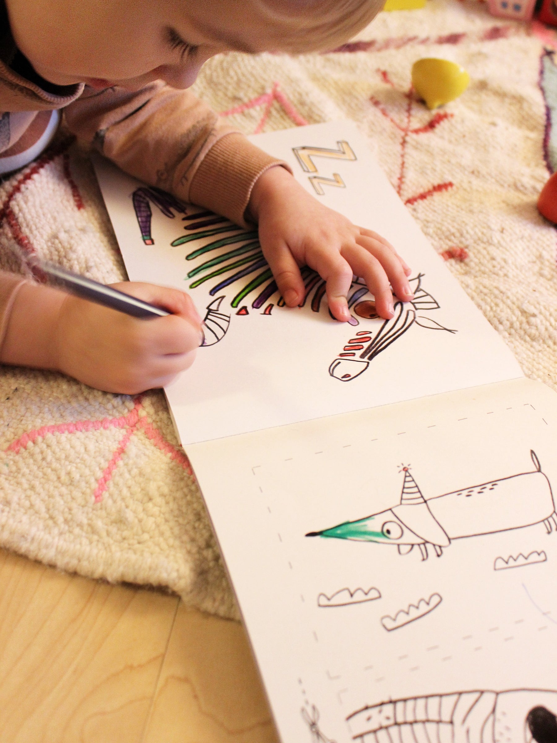 Kind malt im ABC Malbuch von halfbird das Zebra bunt aus